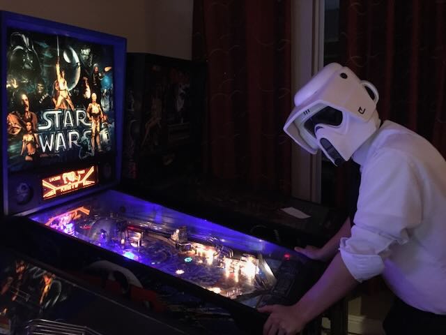 A player in a Stormtrooper helmet bent over a Star Wars machine